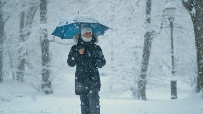 Dogodki v Ljubljani. Na fotografiji oseba z dežnikom v snežnem metežu.